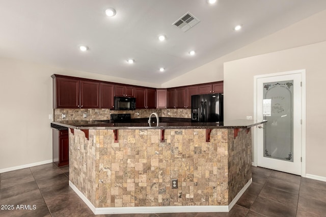 25212 W Maldonado Dr, Buckeye, AZ 85326 - kitchen featuring decorative backsplash, a kitchen breakfast bar, visible vents, black appliances, and lofted ceiling