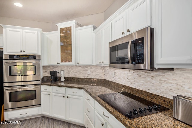 kitchen with white cabinetry, appliances with stainless steel finishes, dark stone counters, and backsplash