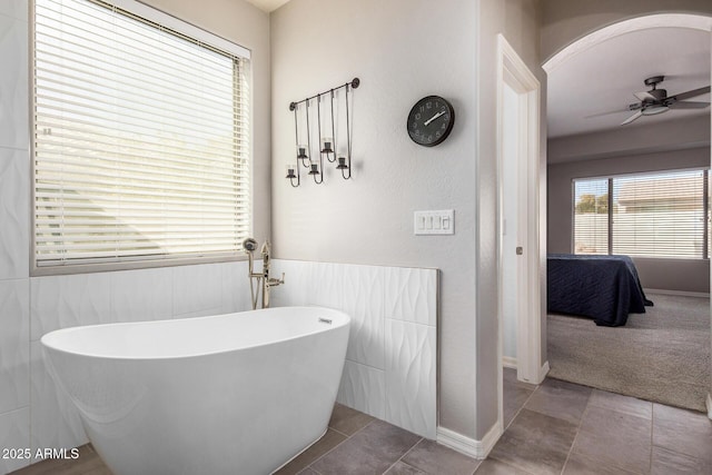 bathroom featuring ceiling fan, a tub to relax in, and tile patterned floors