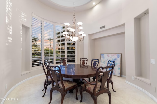 dining room with light carpet, a chandelier, and baseboards