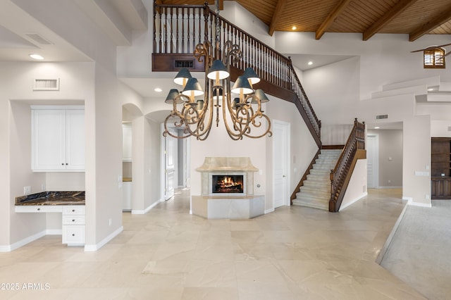unfurnished living room featuring a high ceiling, arched walkways, wooden ceiling, stairway, and baseboards