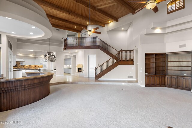 living room with a ceiling fan, a high ceiling, wood ceiling, stairway, and a chandelier