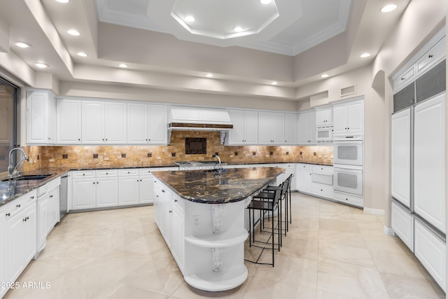 kitchen with a sink, white appliances, exhaust hood, recessed lighting, and white cabinetry
