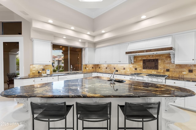 kitchen with a sink, white cabinets, recessed lighting, and a kitchen breakfast bar