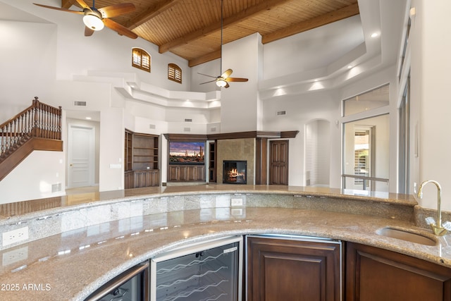 kitchen featuring a ceiling fan, a sink, a high ceiling, wine cooler, and wooden ceiling