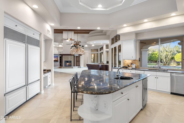 kitchen featuring a sink, dishwasher, a warm lit fireplace, white cabinets, and recessed lighting