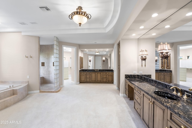 bathroom with recessed lighting, a garden tub, baseboards, two vanities, and a walk in shower