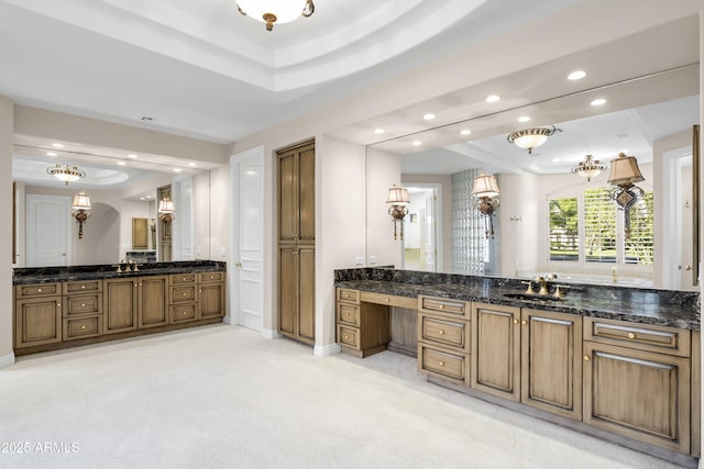 bathroom featuring a raised ceiling, recessed lighting, two vanities, and baseboards