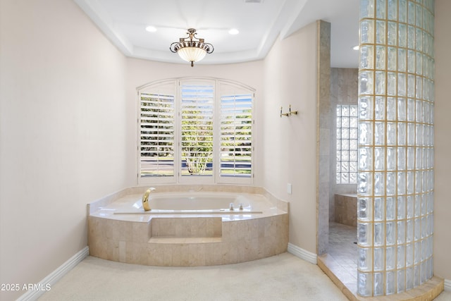 bathroom featuring healthy amount of natural light, a garden tub, baseboards, and walk in shower