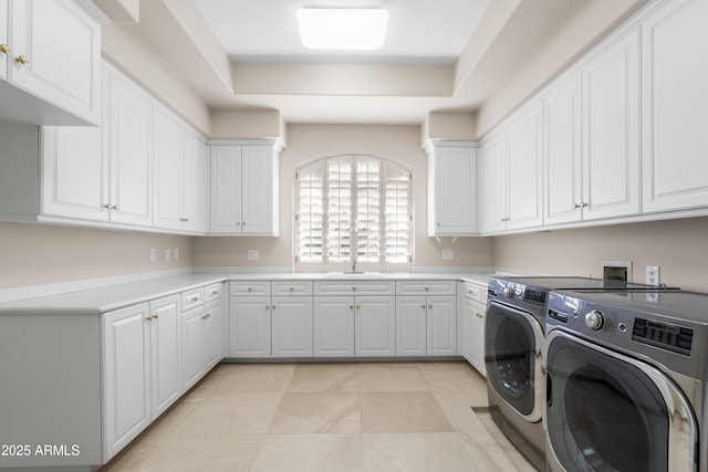 clothes washing area featuring washer and dryer, cabinet space, and light tile patterned floors