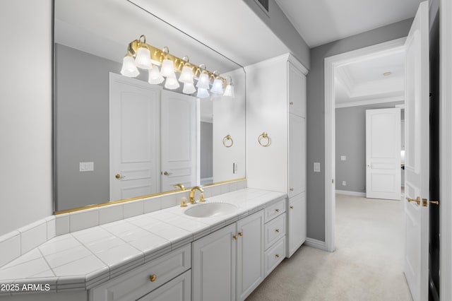 bathroom with ornamental molding, a raised ceiling, baseboards, and vanity