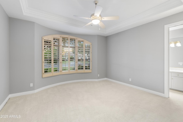 empty room featuring light colored carpet, a tray ceiling, ceiling fan, and baseboards