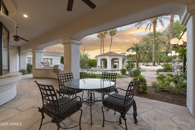 view of patio with ceiling fan, a gazebo, an outdoor kitchen, and a grill