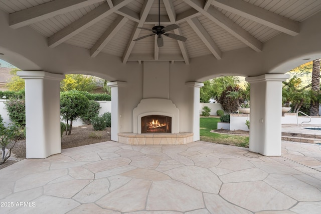 view of patio / terrace with a lit fireplace, ceiling fan, a gazebo, and fence