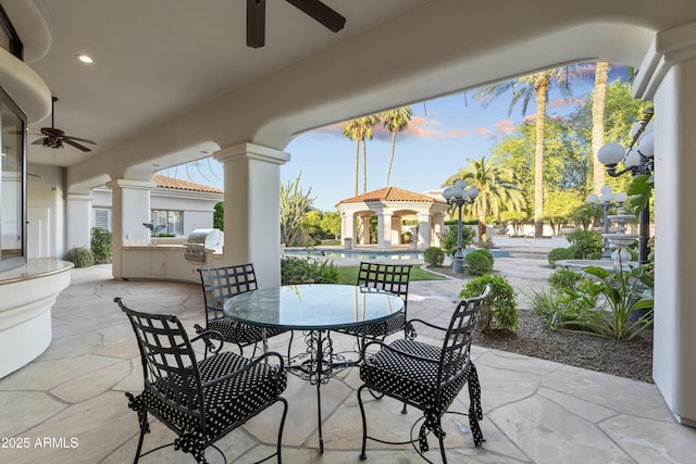 view of patio featuring ceiling fan, an outdoor kitchen, outdoor dining area, and an outdoor pool