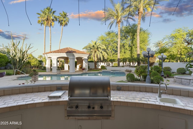 view of patio with a sink, a gazebo, area for grilling, an outdoor pool, and fence