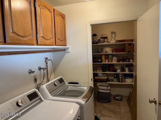 clothes washing area with tile patterned floors, separate washer and dryer, and cabinets