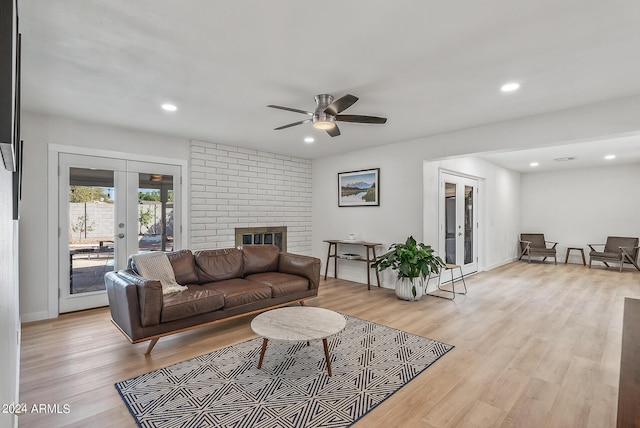 living room featuring light hardwood / wood-style floors, ceiling fan, french doors, and a fireplace