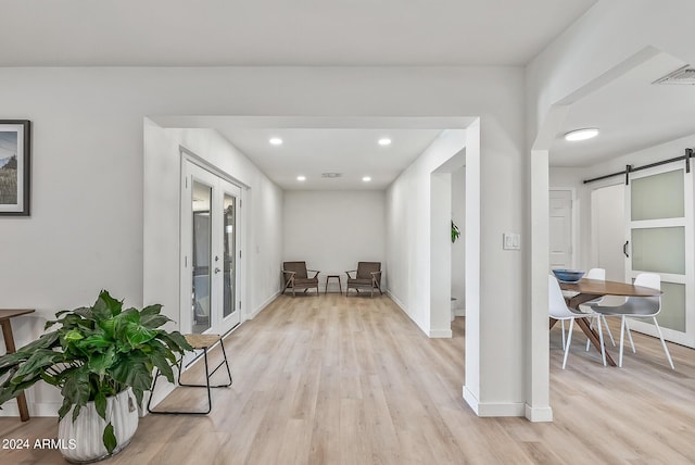 hallway featuring a barn door, french doors, and light hardwood / wood-style floors