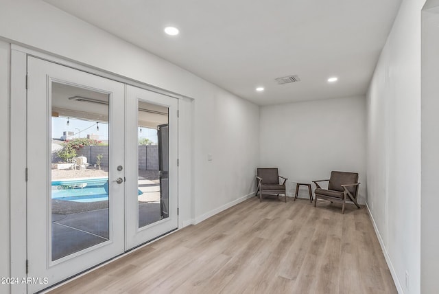 living area with french doors and light hardwood / wood-style flooring