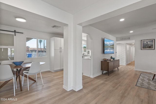 dining room featuring a barn door and light wood-type flooring