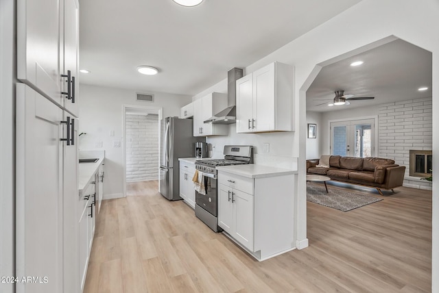 kitchen with ceiling fan, wall chimney range hood, white cabinetry, appliances with stainless steel finishes, and french doors