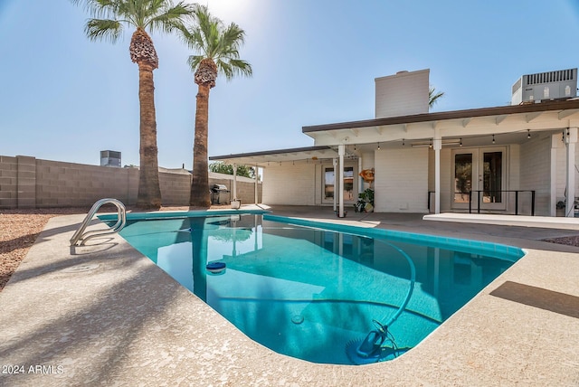 view of swimming pool featuring central AC unit, a patio area, and french doors