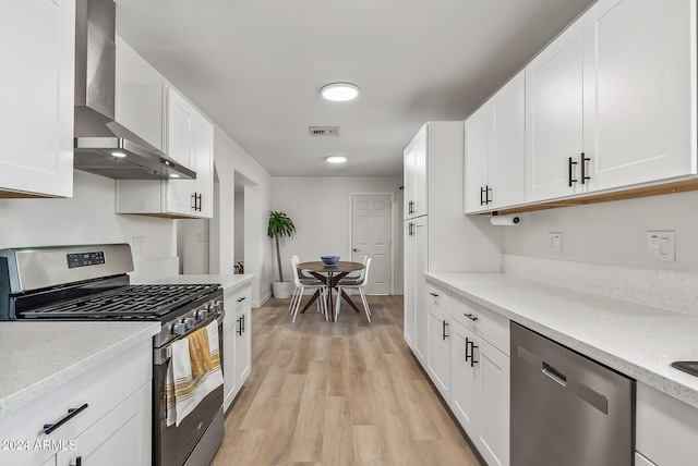 kitchen featuring white cabinetry, appliances with stainless steel finishes, and wall chimney exhaust hood