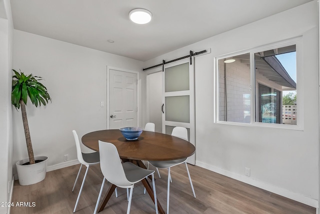 dining space featuring a barn door and hardwood / wood-style flooring