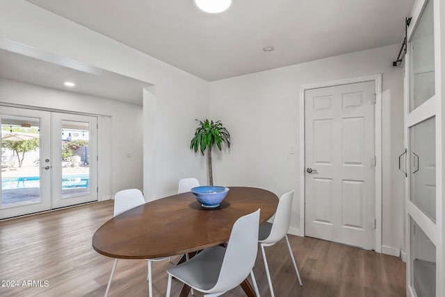 dining space featuring wood-type flooring, a barn door, and french doors