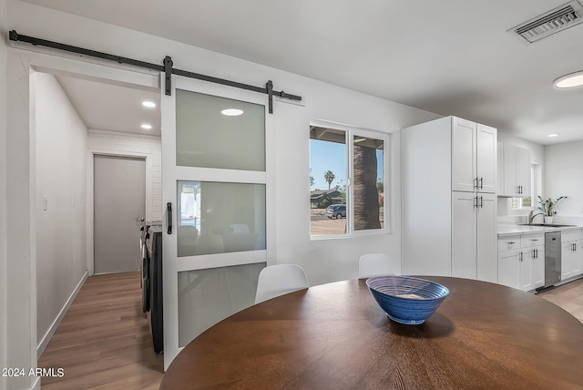 dining room featuring a barn door, sink, and light hardwood / wood-style flooring