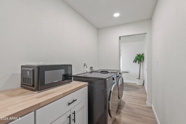 clothes washing area with separate washer and dryer and light hardwood / wood-style flooring