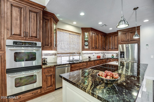 kitchen featuring sink, hanging light fixtures, stainless steel appliances, dark stone counters, and decorative backsplash