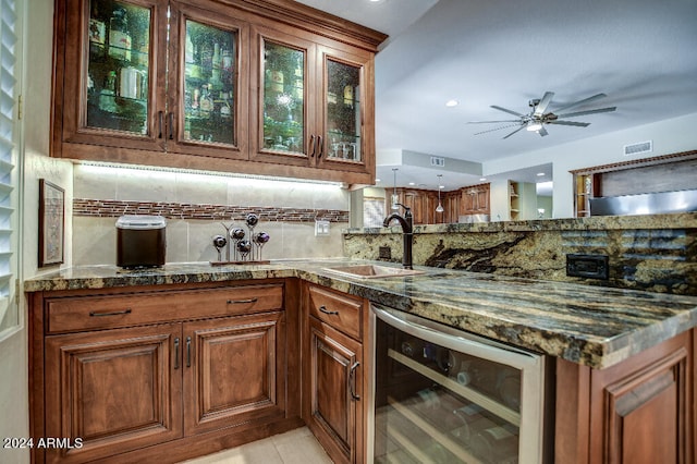 bar with backsplash, dark stone countertops, sink, beverage cooler, and ceiling fan