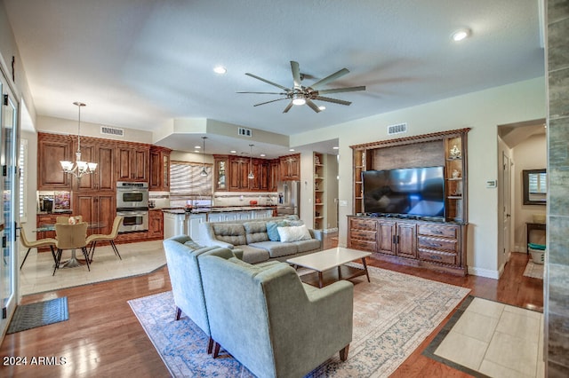 living room with light hardwood / wood-style floors and ceiling fan with notable chandelier