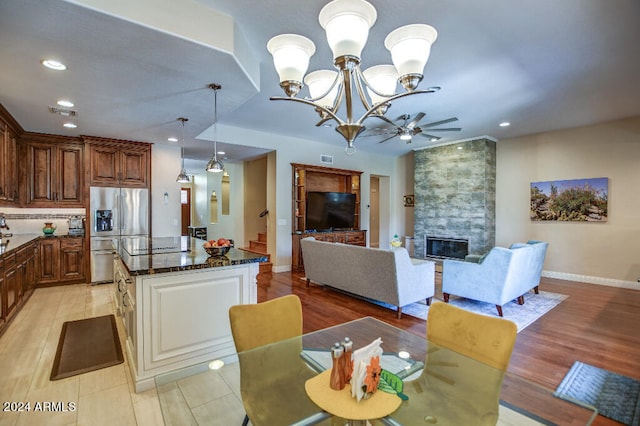 dining area featuring a fireplace, light hardwood / wood-style floors, and ceiling fan