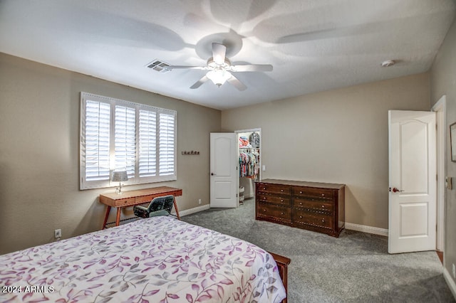 carpeted bedroom with a closet, ceiling fan, and a walk in closet