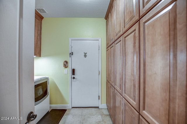 laundry room featuring washer / dryer, cabinets, and light tile patterned floors