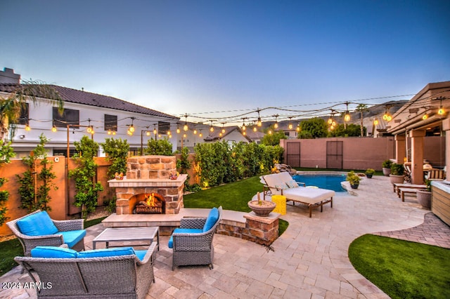 patio terrace at dusk featuring a fenced in pool and an outdoor living space with a fireplace