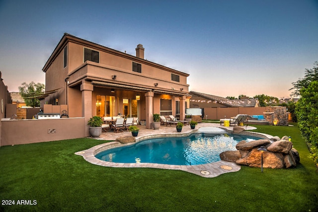 back house at dusk with a lawn, a patio area, a fenced in pool, and outdoor lounge area