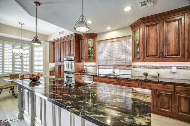 kitchen with decorative backsplash, sink, hanging light fixtures, and stainless steel appliances