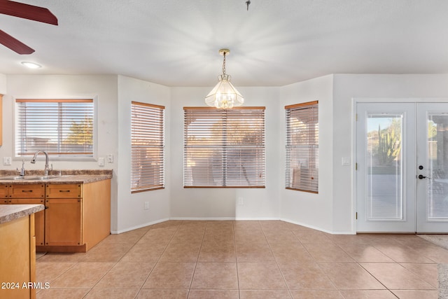 interior space with light tile patterned floors, a wealth of natural light, sink, and french doors