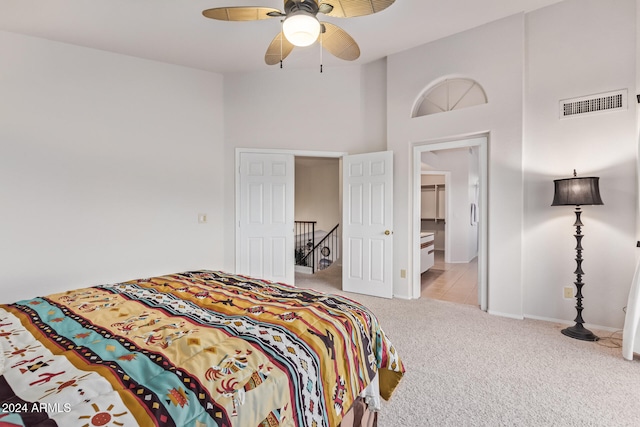 carpeted bedroom with high vaulted ceiling, connected bathroom, and ceiling fan