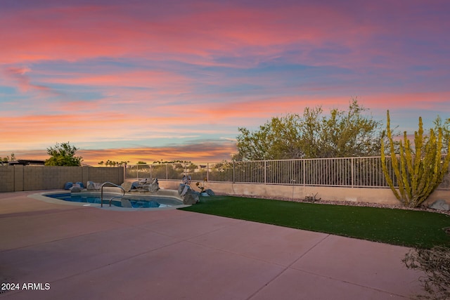 pool at dusk featuring a patio area