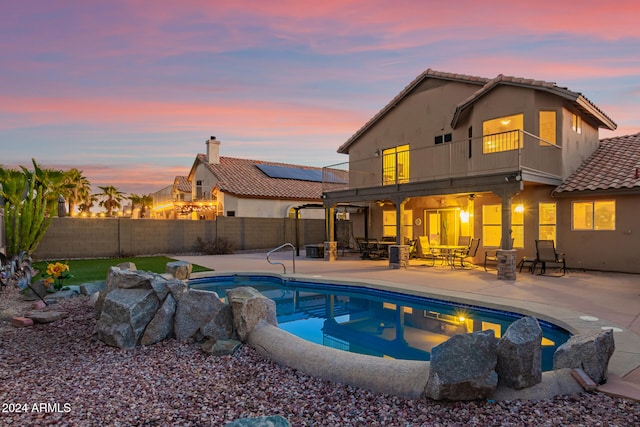 pool at dusk with a patio area