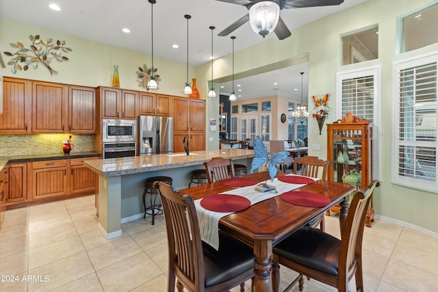 tiled dining space with sink and ceiling fan with notable chandelier