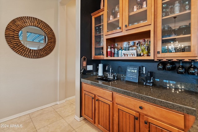 bar with sink, light tile patterned floors, and dark stone counters