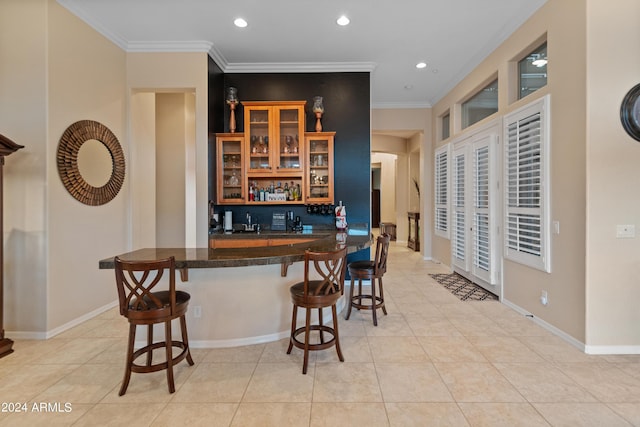 kitchen featuring light tile patterned flooring, ornamental molding, kitchen peninsula, and a breakfast bar area