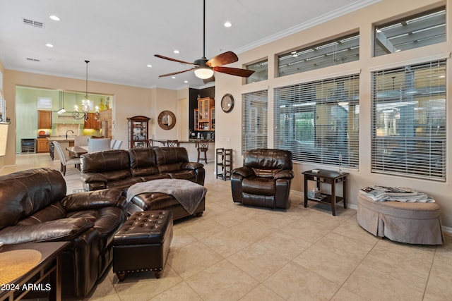 tiled living room with ornamental molding, sink, and ceiling fan with notable chandelier