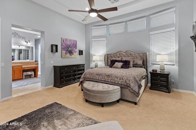 bedroom with ensuite bath, light colored carpet, and ceiling fan